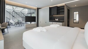 A modern hotel room with a large bed, a desk with a chair, a TV, and a view of the outdoors through large windows. - INVENTIST Hotel Sports Academy (Çekmeköy)