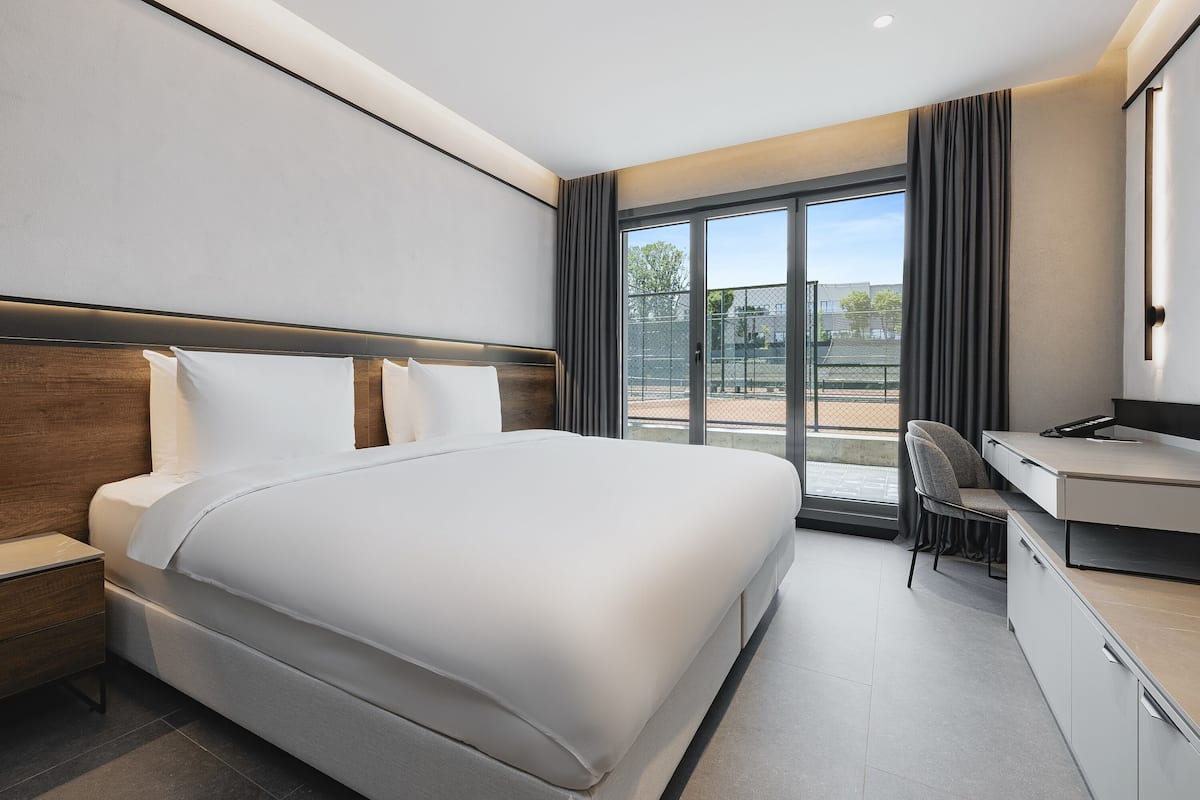 Ein modernes Hotelzimmer mit einem großen Bett, einem Schreibtisch und Blick ins Freie.