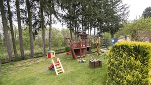 Leikkikenttä, jossa on liukumäki, kiipeilytelineitä ja pieni leikkimökki.