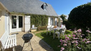 Une maison dotée d’un patio couvert, d’un barbecue et d’une table avec des chaises.