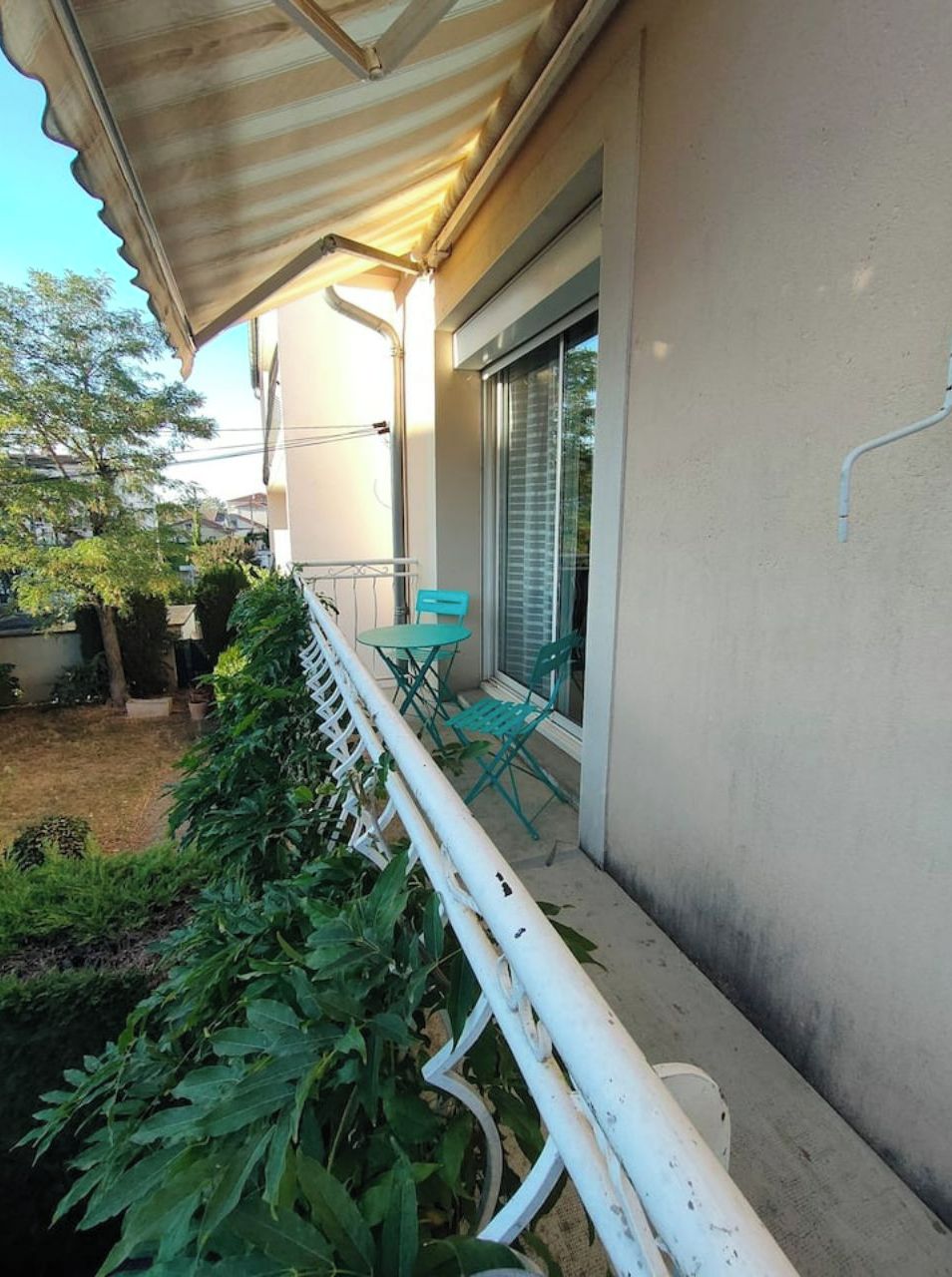 A balcony with a white railing, a table, and two chairs.