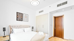 Una camera da letto ordinata con un letto grande, lampade sui comodini, un armadio e una porta.