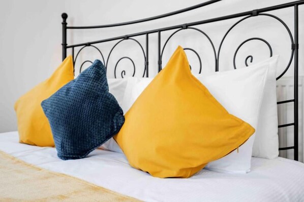 A bed with a metal headboard and pillows in yellow and blue. - Duplex 3 Bedroom Flat Golders Green Central London (London)