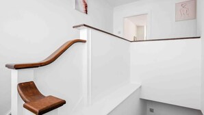 A modern staircase with a wooden handrail and a wooden bench at the bottom. - Duplex 3 Bedroom Flat Golders Green Central London (London)