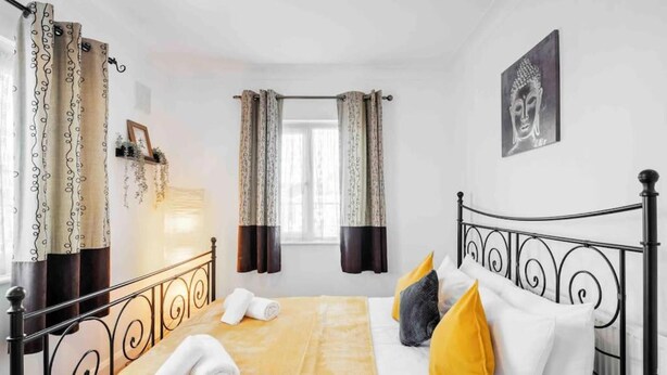 A bedroom with a bed, curtains, a Buddha painting, and a window. - Duplex 3 Bedroom Flat Golders Green Central London (London)
