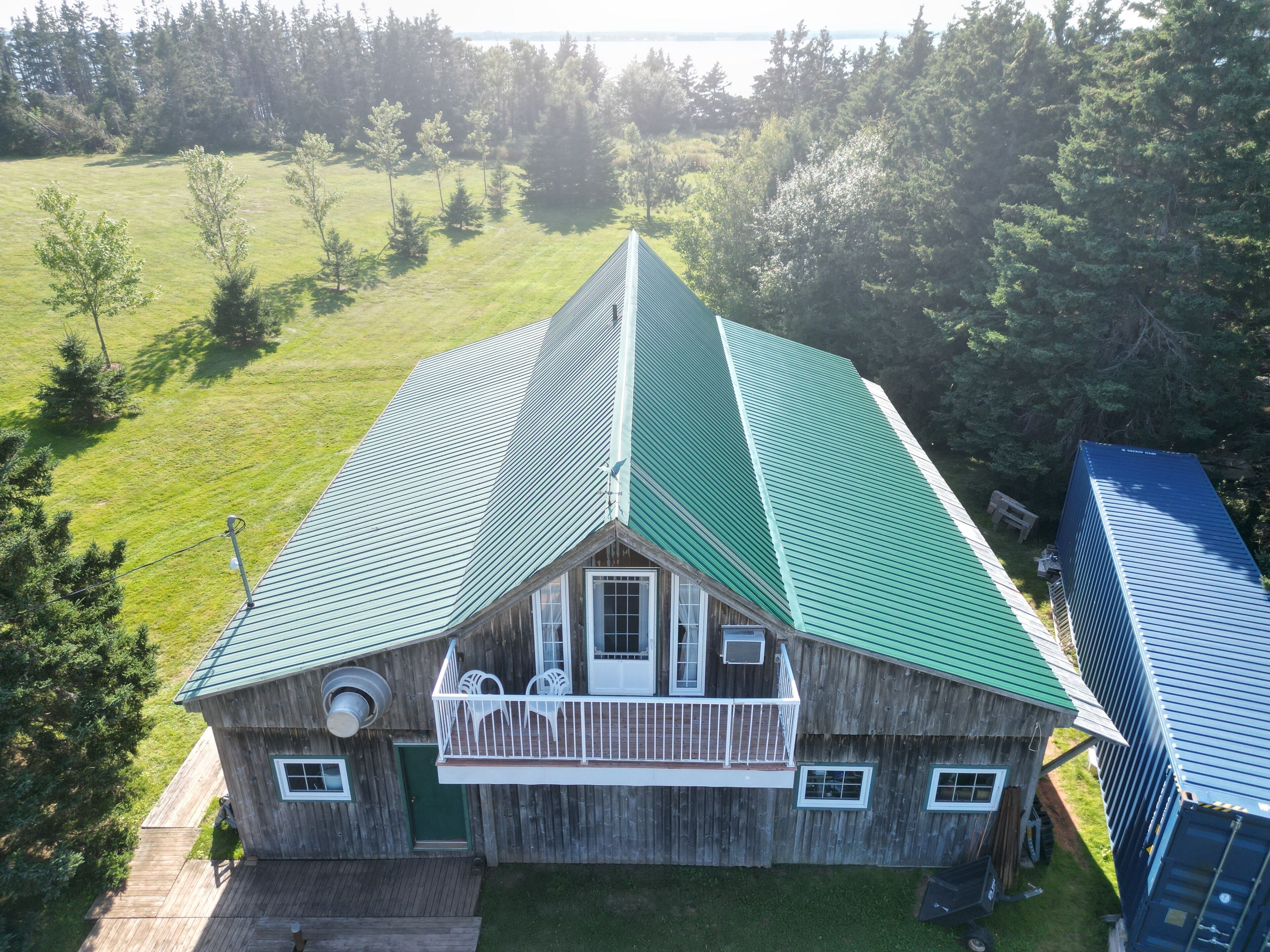 A wooden cabin with a green roof, a balcony, and a small porch.