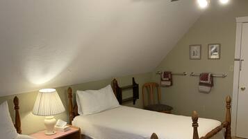 Una habitación con dos camas de madera, un ventilador de techo, una lámpara y una puerta.