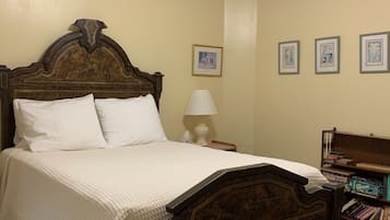 A bedroom with a wooden bed, a ceiling fan, a bedside lamp, and a bookshelf.