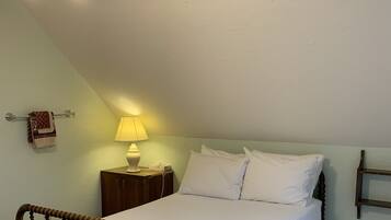 A bedroom with a wooden bed, a nightstand, a lamp, and a ceiling fan.