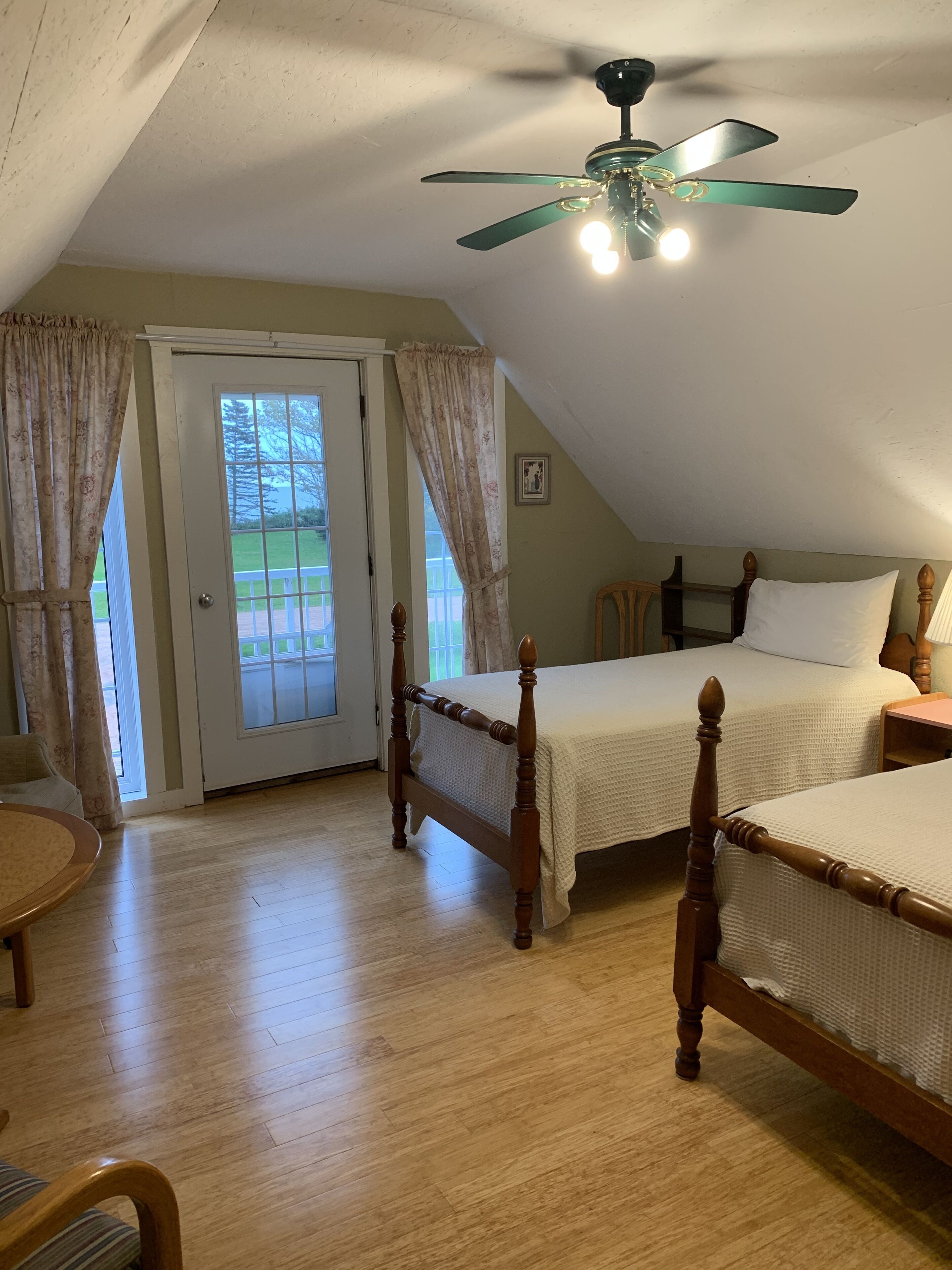A bedroom with two wooden beds, a ceiling fan, and a door leading to an outdoor area.