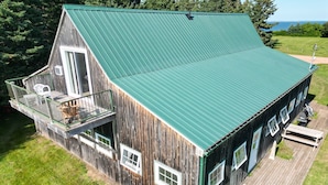 A wooden house with a green metal roof, a balcony, and a wooden deck.