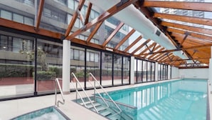 An indoor swimming pool with glass walls, wooden beams, and metal railings. - Central 2BR Apt in Southbank (Southbank)