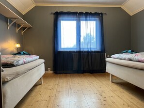 Two single beds with matching headboards, each with a floral-patterned duvet and a neatly folded towel.