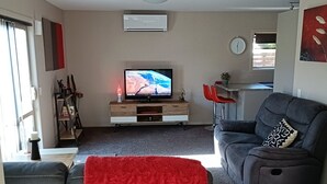 A living room with a TV, sofa, and red blanket. - Executive hideaway<br> (Christchurch)