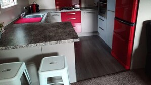 A kitchen with a granite countertop, white and red cabinets, a red refrigerator, and a stainless steel range hood. - Executive hideaway<br> (Christchurch)