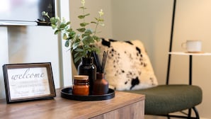 En välkomstskylt för Crescent Apartments, ett litet bord med en växt, ljus och en kaffekopp.