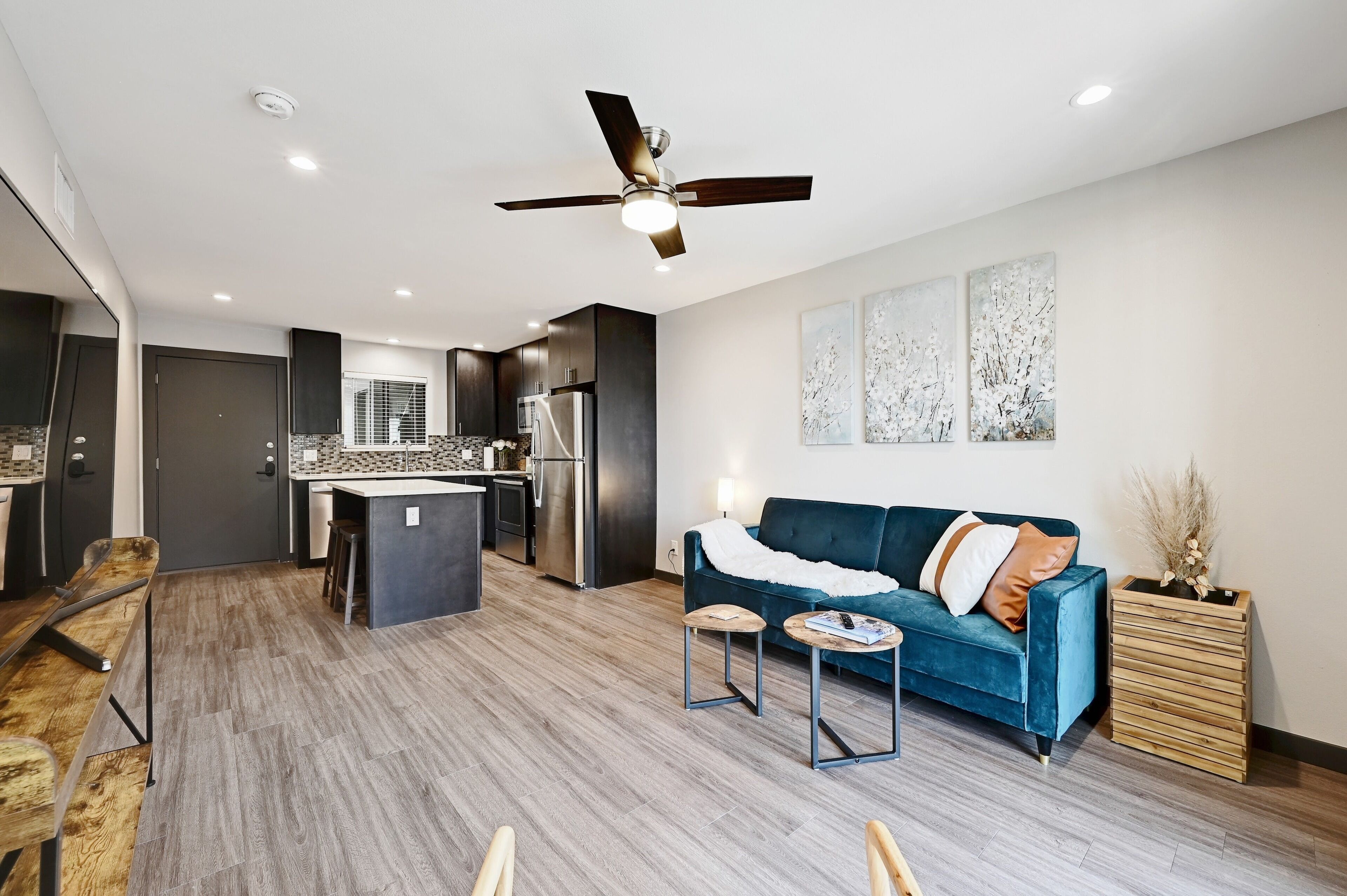 A modern living room with a blue sofa, a coffee table, and a ceiling fan.