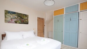 Una camera da letto con un letto grande, una porta in legno e un armadio colorato.