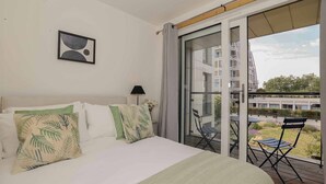 A hotel room with a bed, a view of the city, and a balcony with chairs. - Stylish comfortable apartment in central Kingston - Pass the Keys (Kingston-upon-Thames)