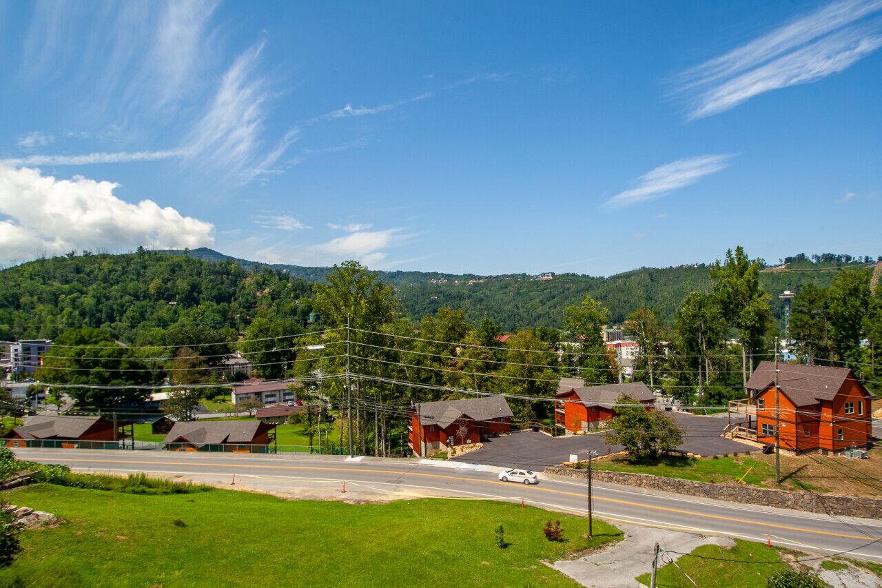 A rural town with red-roofed houses, a main road, and a hilly backdrop.