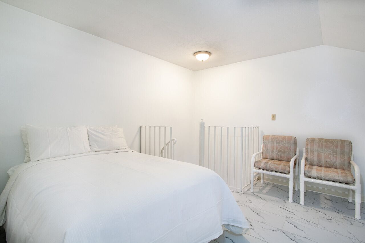 Une chambre à coucher avec un lit, deux chaises et un radiateur.