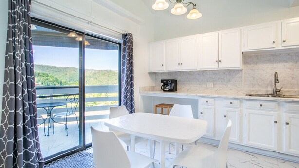 A modern kitchen with white cabinets, a marble countertop, and a coffee maker. - Private Balcony with Scenic Views | Pool & Cozy Fireplace (Gatlinburg)