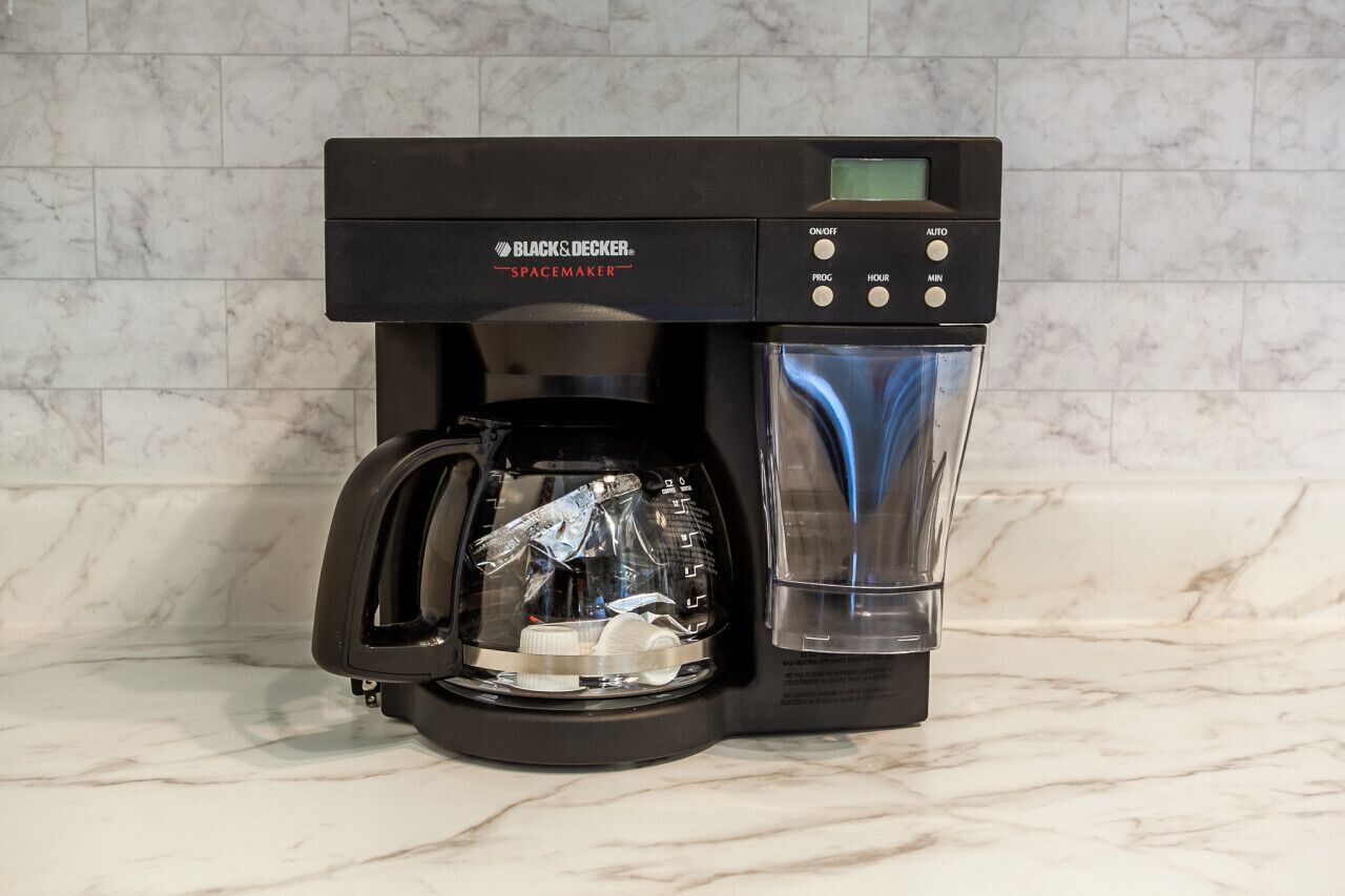 A BLACK & DECKER Spacemaker coffee maker with a digital display, programmable buttons, and a water reservoir.