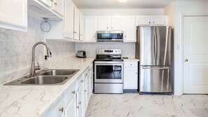 A modern kitchen with white cabinets, stainless steel appliances, and a marble countertop. - Private Balcony with Scenic Views | Pool & Cozy Fireplace (Gatlinburg)
