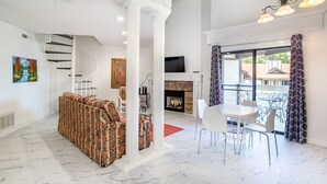 A spacious living area with a sofa, dining table, and chairs, a fireplace, and a staircase. - Private Balcony with Scenic Views | Pool & Cozy Fireplace (Gatlinburg)