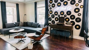 A modern living room with a sectional sofa, a coffee table, and a record wall. - All Shook Up at Pettigrew Adventures (Memphis)