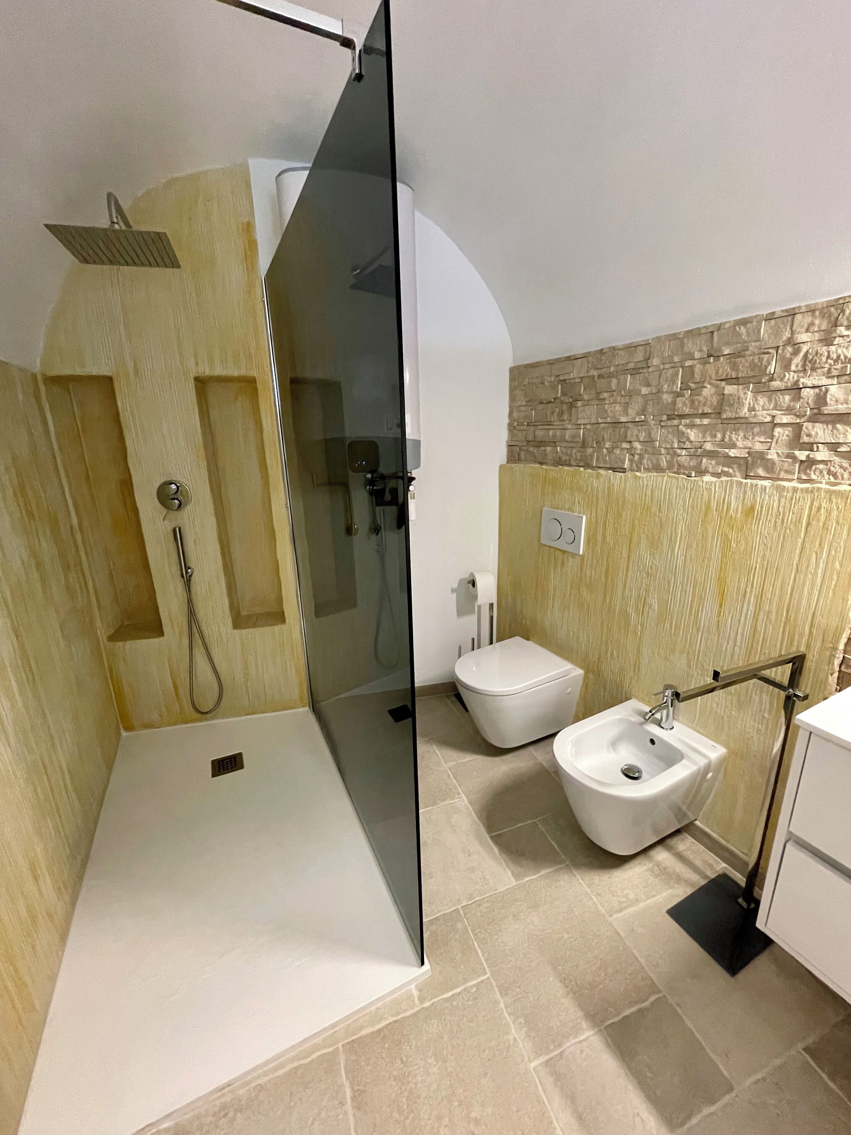 A modern bathroom with a glass-enclosed shower, a toilet, and a bidet.