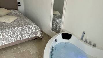 Una camera da letto con un letto grande, un bagno con una vasca e uno specchio a parete.