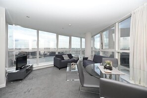Een moderne woonkamer met een groot raam, een flatscreen-tv, een bank en een salontafel.