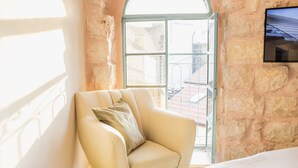 Una habitación con un ventanal amplio, un sillón color beige y una cama.