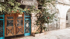 Un edificio con un letrero de Guinness, puertas de madera con detalles de metal azul y una pared de ladrillo.