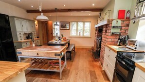 A kitchen with a wooden table, a brick oven, and a countertop with a toaster.