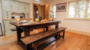 A dining area with a wooden table, benches, and a kitchen in the background.