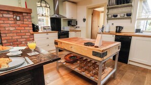 A kitchen with a wooden island, a brick wall, and a brick fireplace.