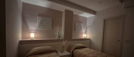 A bedroom with two beds, a nightstand, decorative wall art, and a door.