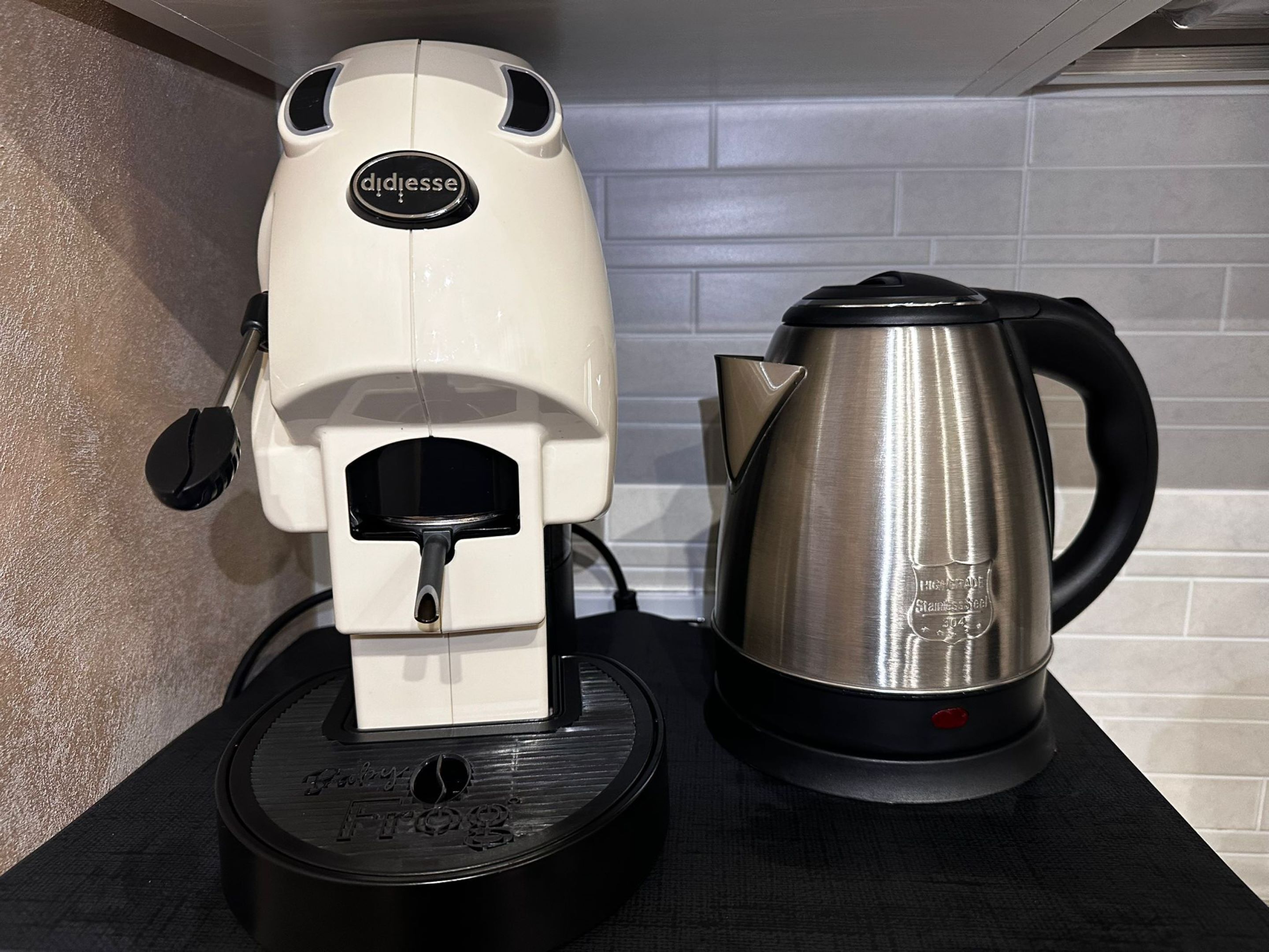 A coffee machine and a stainless steel kettle on a countertop.