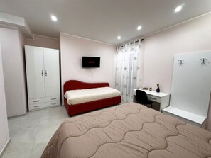 A bedroom with a bed, a desk, a wardrobe, and a TV mounted on the wall. - DOMUS BALCANTE (Pompei)