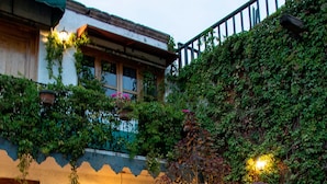 A rustic building with a stone patio, a wooden door, and a window with a light fixture. - Hotel Casa del Fraile (Morelia)