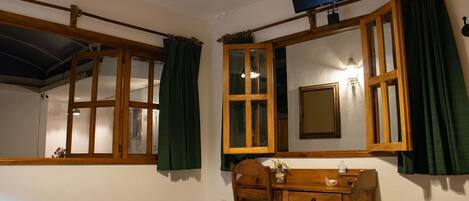Une chambre à coucher comprenant un lit, un bureau en bois, une chaise, un téléviseur et une fenêtre avec des rideaux.