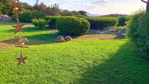 A well-maintained garden with neatly trimmed hedges, a star-shaped wind chime, and a clear view of the surrounding landscape. - Cala Paradiso Apt "Casa Agave" ⭐⭐⭐⭐ Sea View, Garden, WiFi, AC (Salina Bamba)