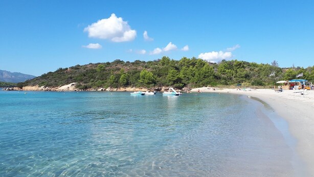 A beach with clear water, boats, and a forested hillside. - Cala Paradiso Apt "Casa Agave" ⭐⭐⭐⭐ Sea View, Garden, WiFi, AC (Salina Bamba)