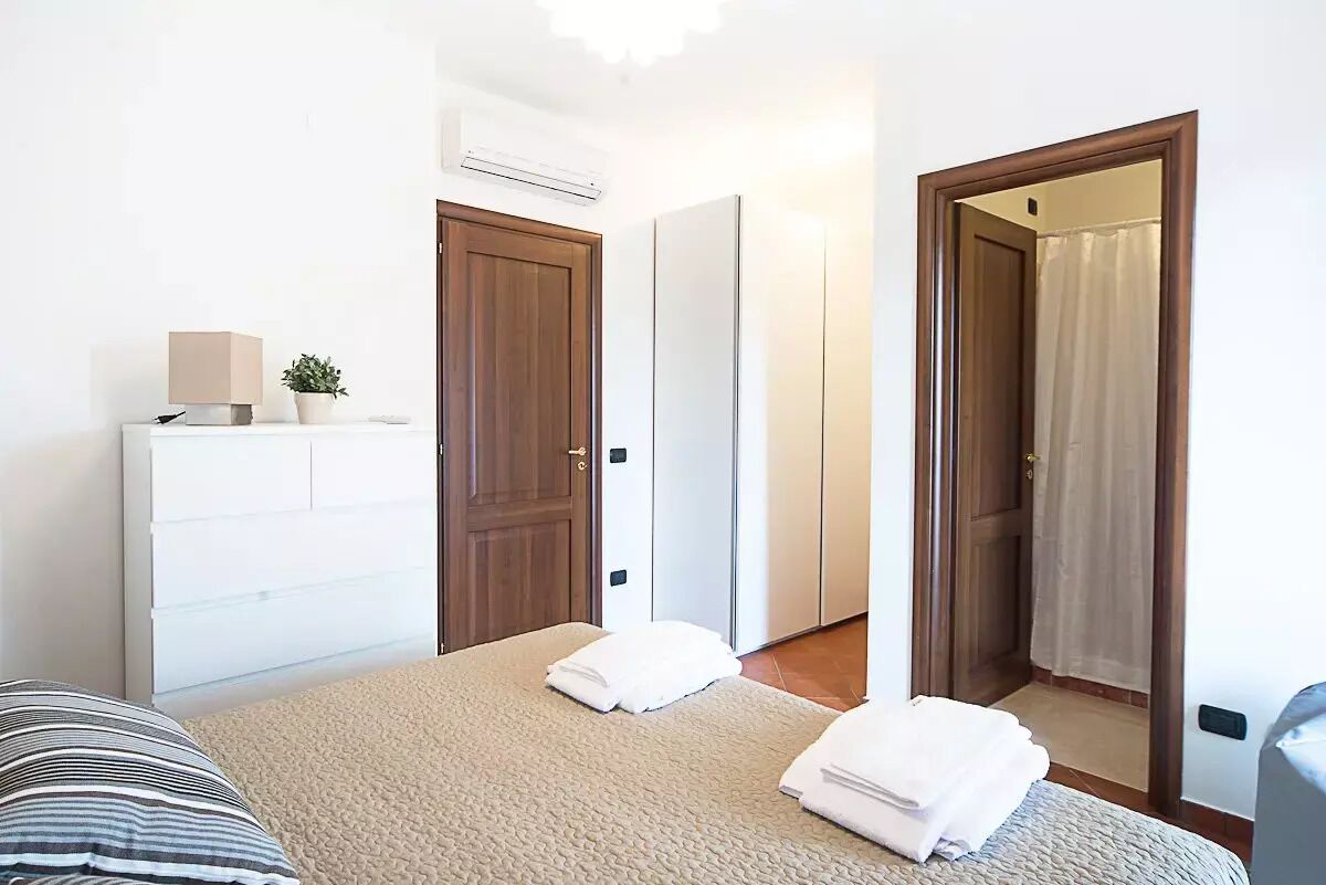 Quarto de hotel com cama, penteadeira, espelho e porta para um banheiro.