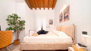 Une chambre à coucher avec un lit, un bureau, une chaise, une plante et des œuvres d’art accrochées aux murs.