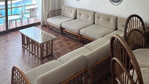 Una habitación con un ventanal grande, un ventilador de techo, un sofá, una mesa y dos sillas.