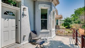 Una casa con puerta blanca, una ventana y un pequeño porche con una silla.