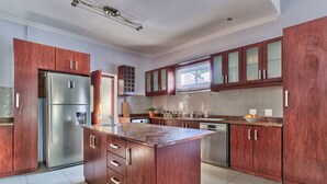 A modern kitchen with wooden cabinets, a stainless steel refrigerator, and a large island.